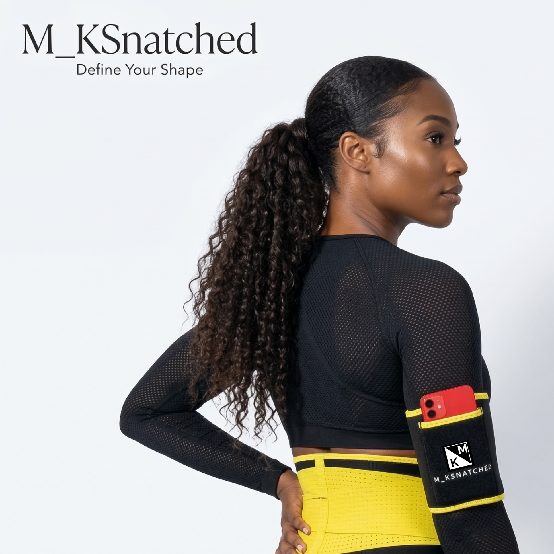 Woman wearing a black and yellow athletic outfit with a phone pocket, branded 'M_KSnatched'.