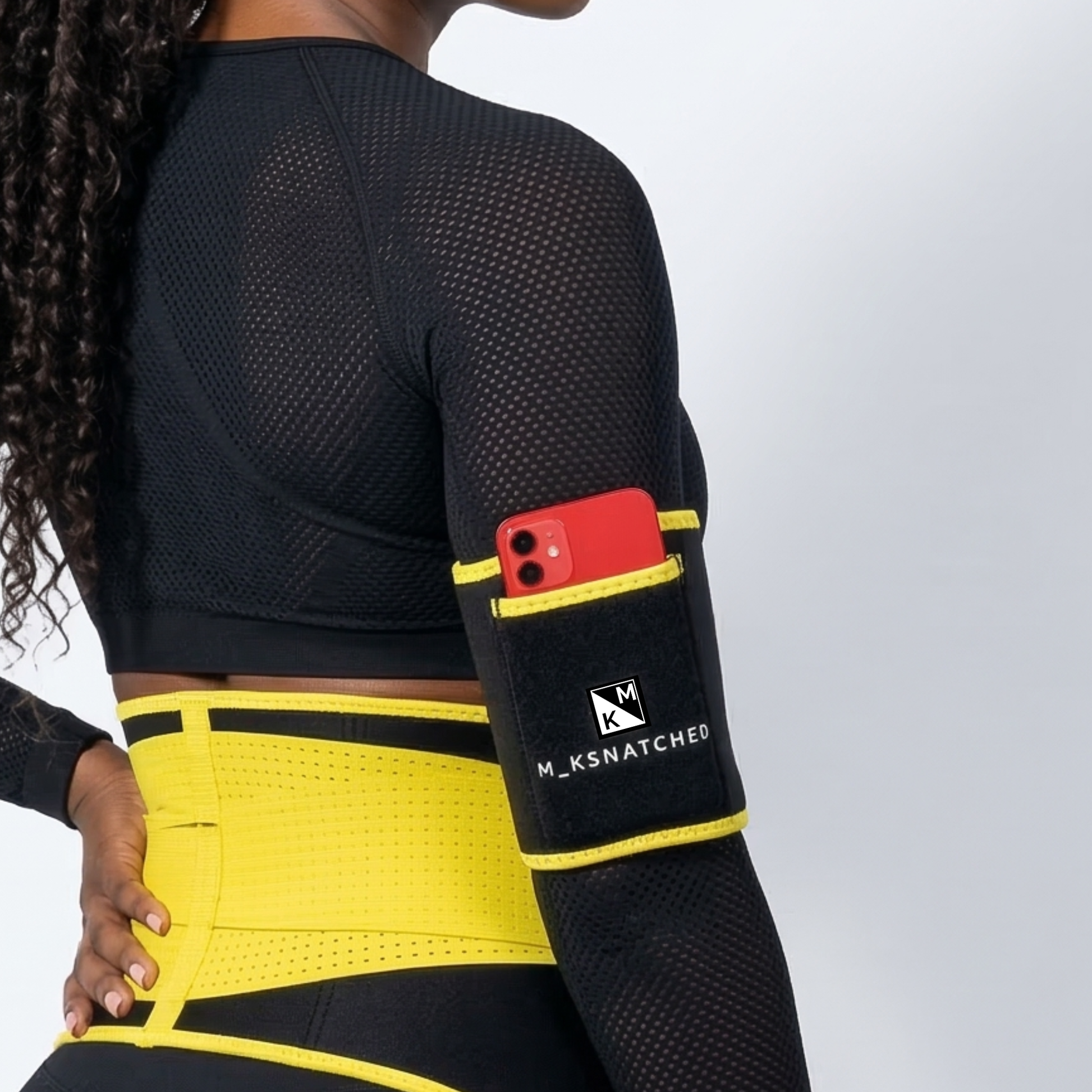 Person wearing a black and yellow compression garment with a phone pocket, branded 'M_KSNATCHED'.