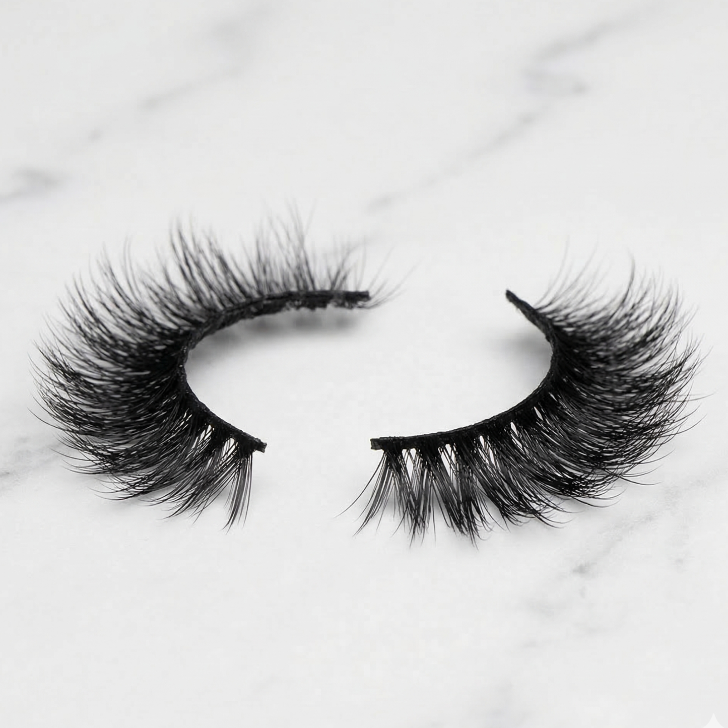 Pair of false eyelashes on a light marble background