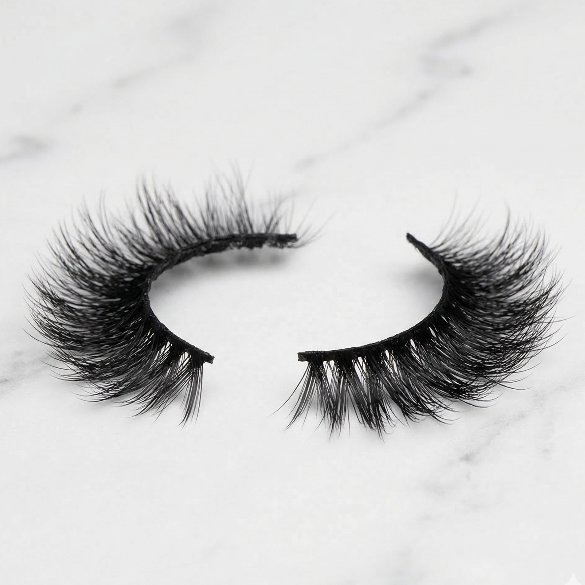 Pair of false eyelashes on a light marble background