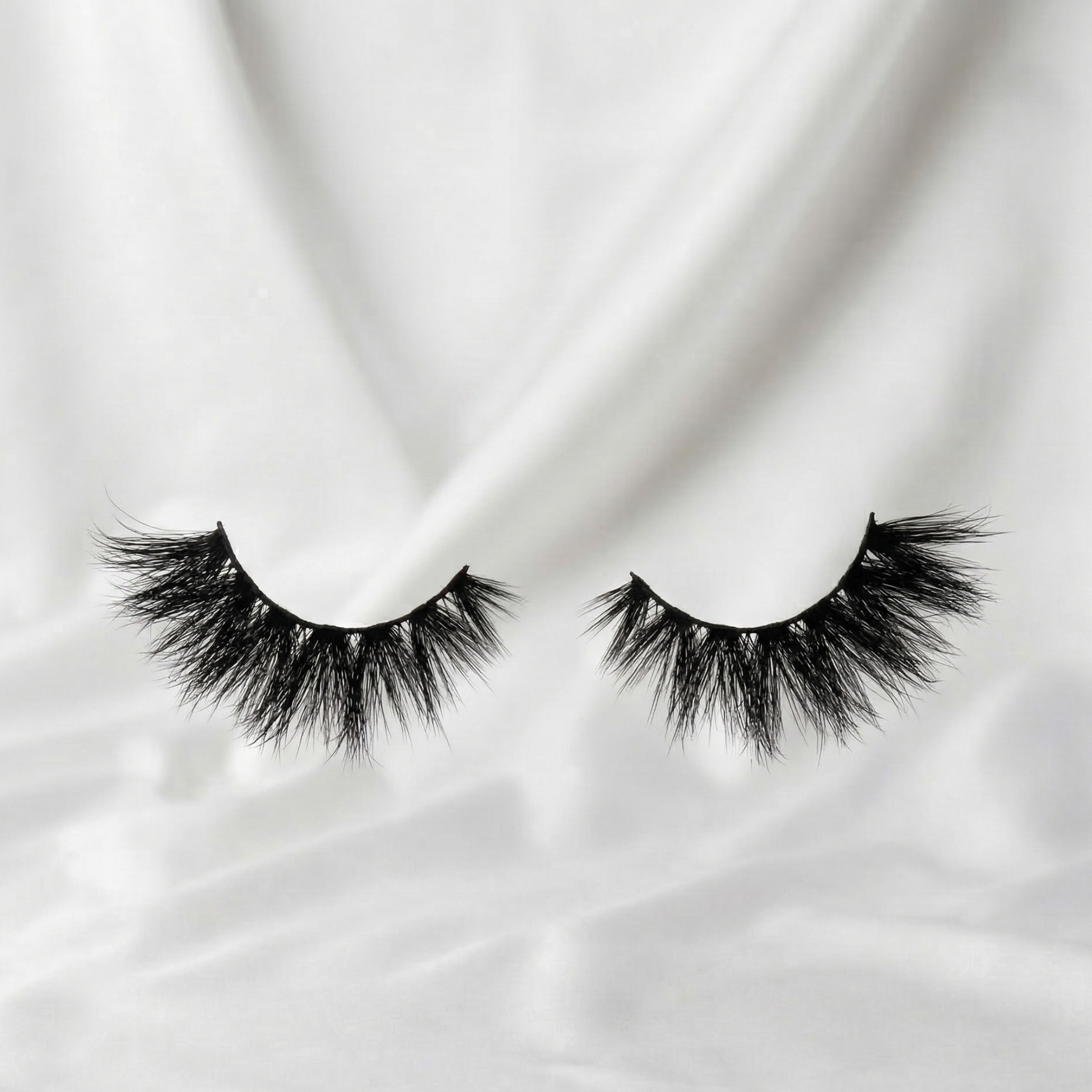 Pair of false eyelashes on a white fabric background