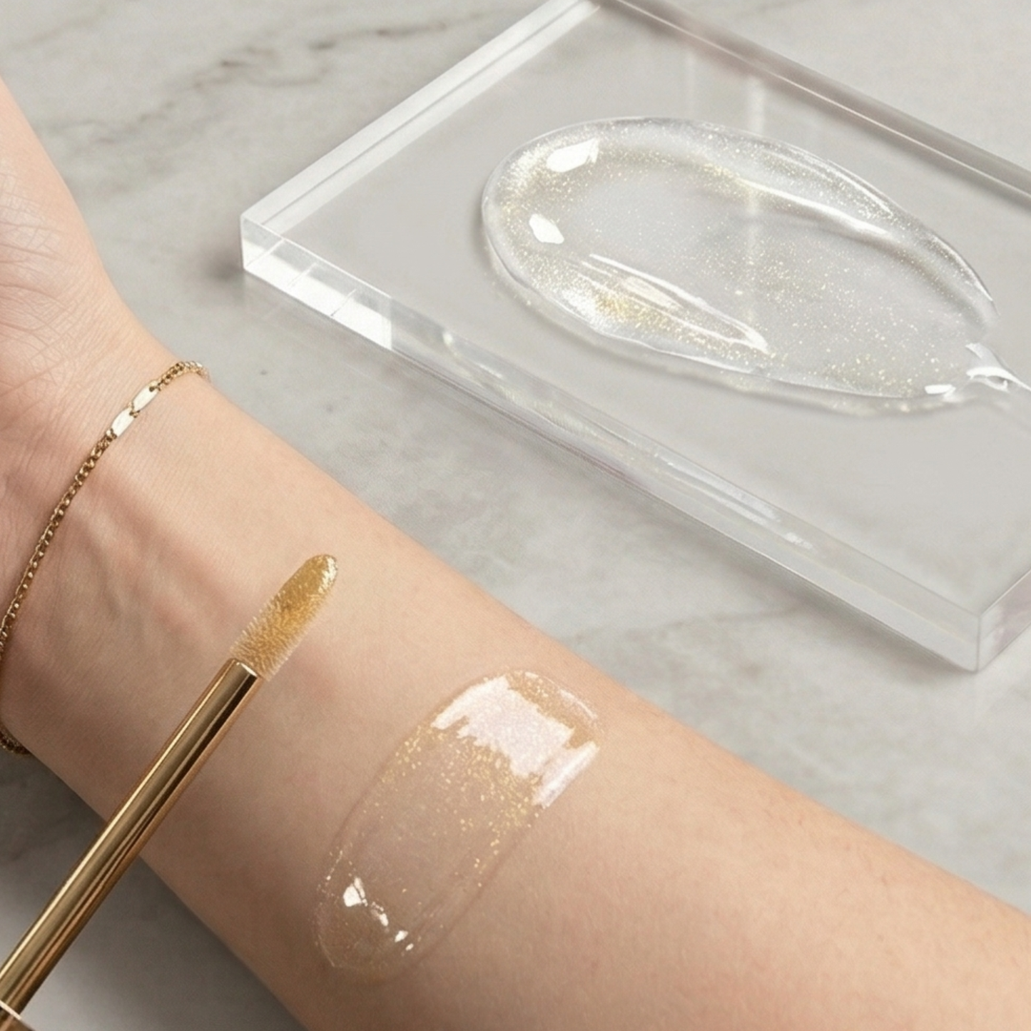 Gold makeup brush applying cream to a wrist with a clear container in the background