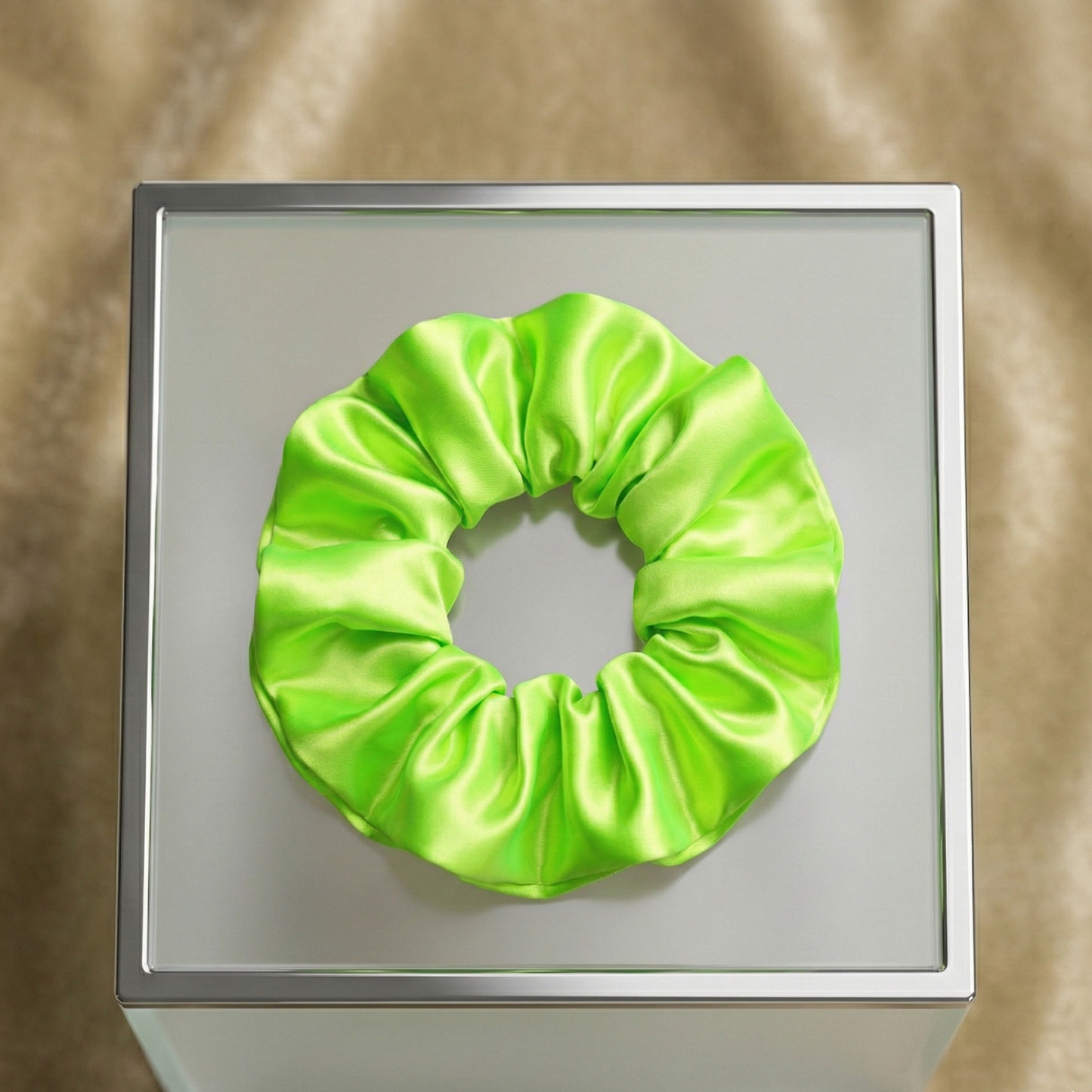 Green scrunchie on a metallic surface with a reflective background