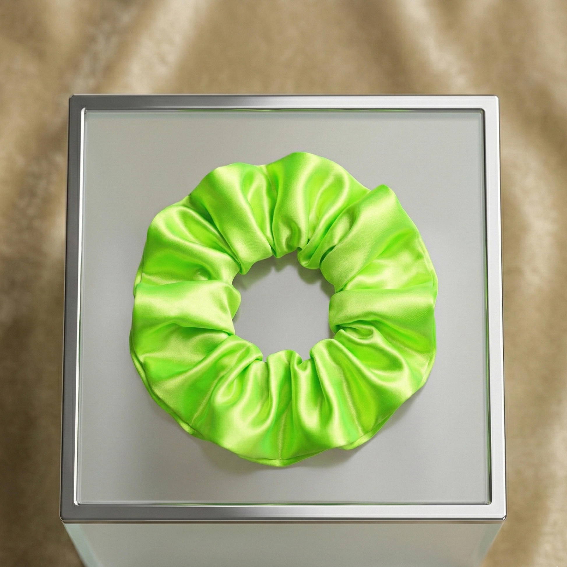 Green scrunchie on a metallic surface with a reflective background