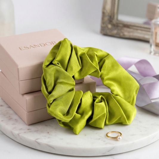 Green scrunchie on a marble surface with a box and jewelry in the background